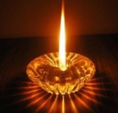 Flamme d'une bougie dans une coupe de verre